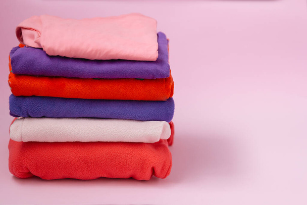 pilha de roupas ou toalhas dobradas em um fundo rosa
 - Foto, Imagem