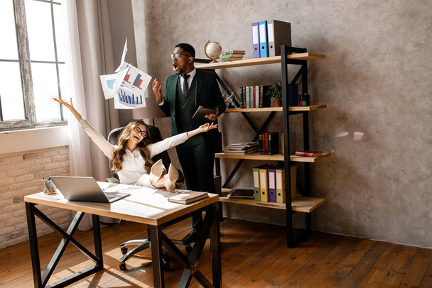 Young business people working in office throwing documents in air  - 写真・画像