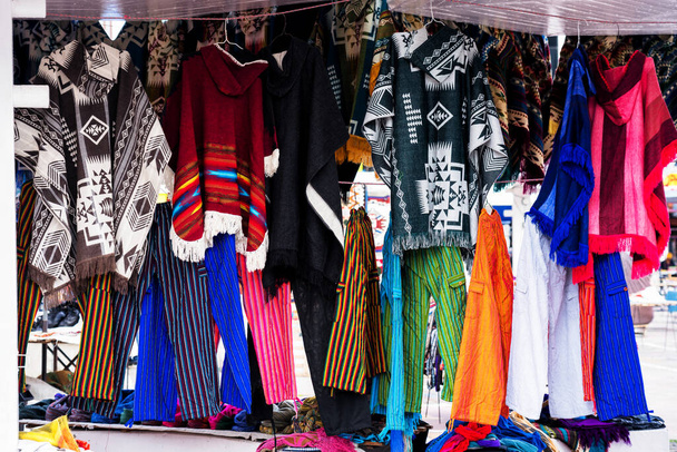Ponchos traditionnels en différentes couleurs exposés au marché artisanal d'Otavalo en Équateur. - Photo, image