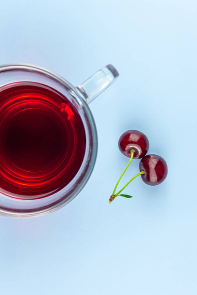 A cup of cherry kampot and two cherries on a blue background - Photo, image