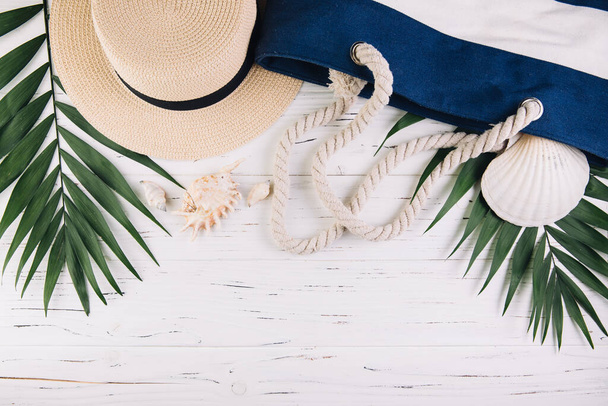 Concepto de vacaciones de verano. Bolsa de playa y accesorios en mesa de madera blanca. Vista superior y plano laico
 - Foto, Imagen