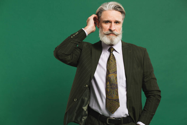 スタイリッシュな髭を生やした中年男性でカーキスーツで緑の背景 - 写真・画像