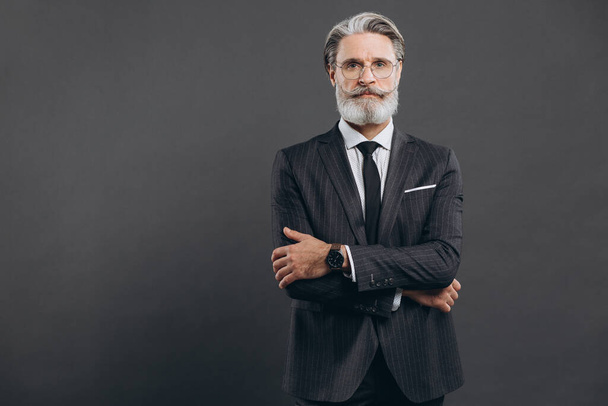 Homme barbu mature d'affaires et à la mode en costume gris avec l'espace de copie gris - Photo, image