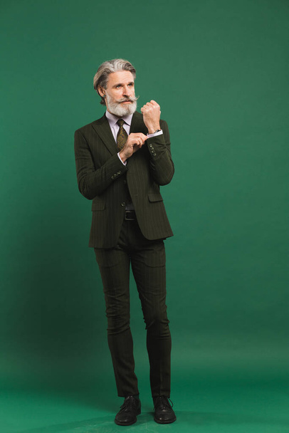 Stylish bearded middle-aged man in khaki suit on green background - Фото, зображення
