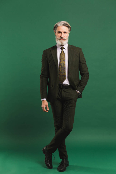 Elegante uomo barbuto di mezza età in tuta kaki su sfondo verde - Foto, immagini