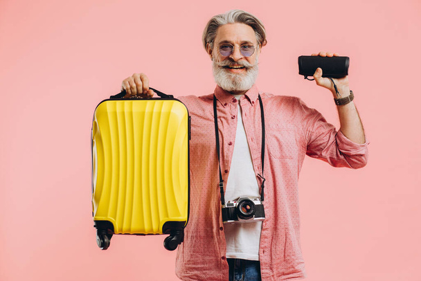 Happy parrakas tyylikäs mies aurinkolasit kamera tilalla matkalaukku ja kannettava kaiutin - Valokuva, kuva