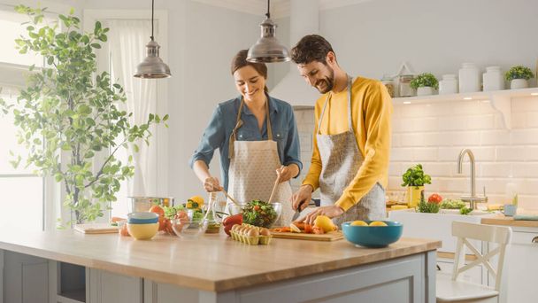 In Kitchen: Perfectly Happy Couple Preparing Healthy Food, Lots of Vegetables. Man Juggles with Fruits, Makes Her Girlfriend Laugh. Lovely People in Love Have Fun - Фото, изображение