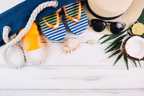 Concepto de vacaciones de verano. Bolsa de playa y accesorios en mesa de madera blanca. Vista superior y plano laico
 - Foto, imagen