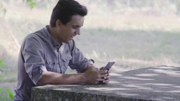 Teenager lacht, während er Handy auf dem Feld sieht - Filmmaterial, Video