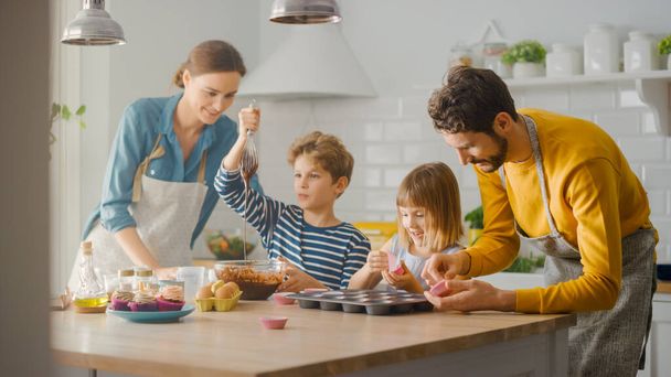 In the Kitchen: Family of Four Cooking Muffins Together. Mother and Daughter Mixing Flour and Water to Create Dough for Cupcakes, Father, Son Preparing Paper Lines for Pans. Children Helping Parents - Fotoğraf, Görsel