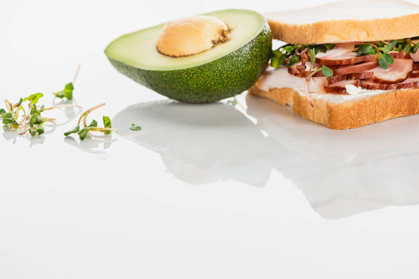 fresh delicious sandwich with meat and sprouts on white surface near avocado - Photo, Image