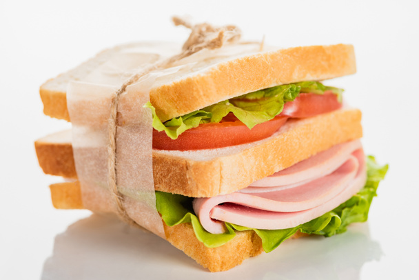 sanduíche delicioso fresco com salsicha fatiada e alface na superfície branca
 - Foto, Imagem