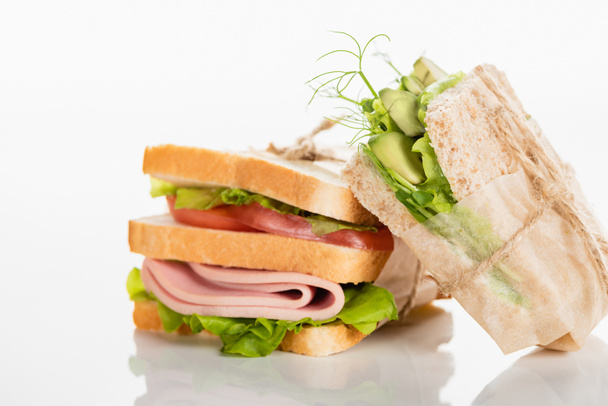 fresh delicious sandwiches with sliced sausage and green vegetables on white surface - Foto, afbeelding