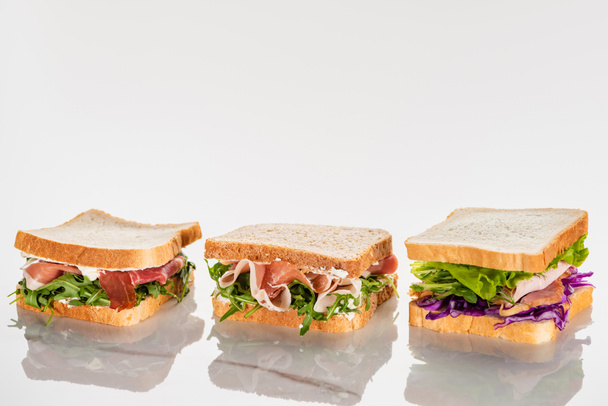 čerstvé zelené sendviče s avokádem a jamonem na mramorovém bílém povrchu - Fotografie, Obrázek