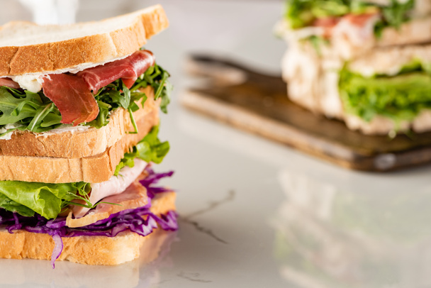 selective focus of fresh sandwiches with meat on marble white surface - Photo, Image