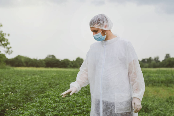 Man in beschermend pak, medisch masker en rubberen handschoenen ter bescherming tegen bacteriën en virussen - Foto, afbeelding