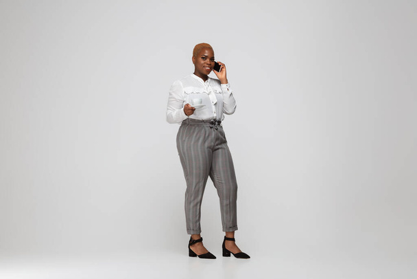 Young african-american woman in office attire on gray background. Bodypositive female character. plus size businesswoman - 写真・画像