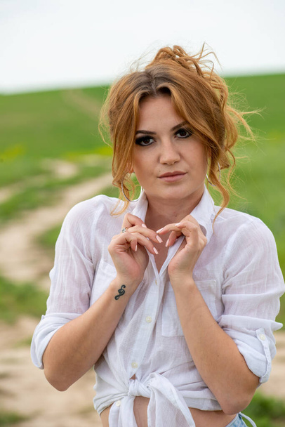 beautiful woman wearing white shirt posing at field - Фото, изображение