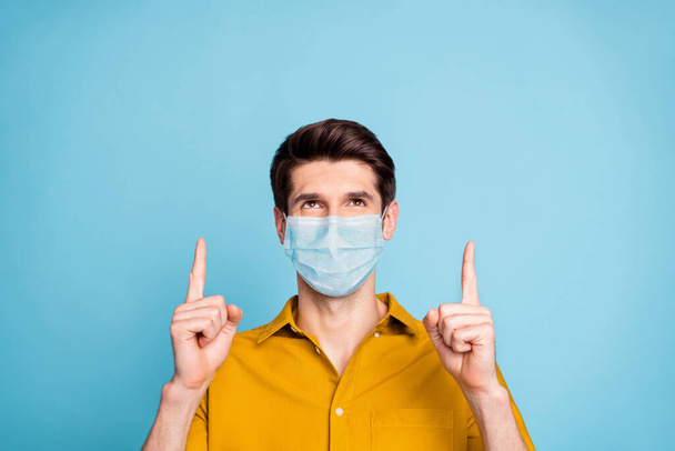 Close-up portrait of his he nice healthy guy wearing safety mask pointing up copy space information stop influenza mers cov pneumonia symptom therapy isolated pastel color background - Photo, Image