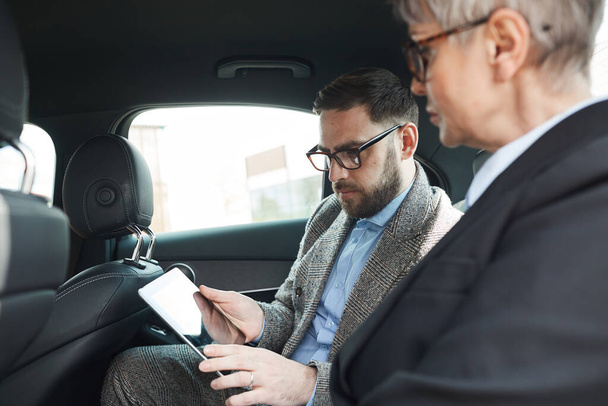 Biznesmeni korzystający z tabletu w samochodzie - Zdjęcie, obraz