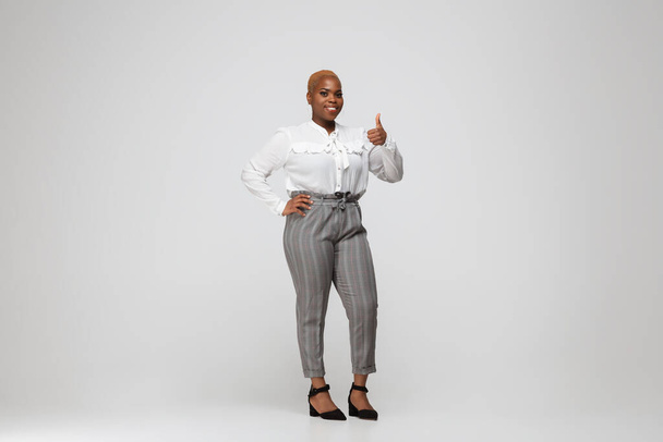 Young african-american woman in office attire on gray background. Bodypositive female character. plus size businesswoman - Foto, Imagen