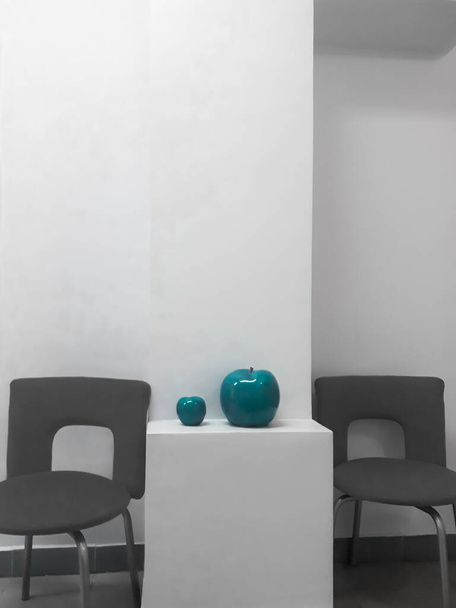 İç mekanın ayrıntıları - beyaz bir duvar, ofis sandalyeleri ve turkuaz renkli iki seramik elma.. - Fotoğraf, Görsel