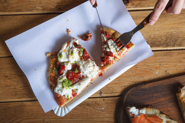Le mani di una donna tagliano una fetta di pizza. La pizza italiana viene mangiata con una forchetta e un coltello. Primo piano - Foto, immagini