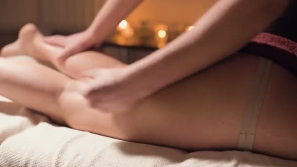 Close-up professional hip massage in the spa salon with a pleasant warm light. A male masseur does a premium massage to a female client. Fighting cellulite and professional body and skin care - Materiał filmowy, wideo