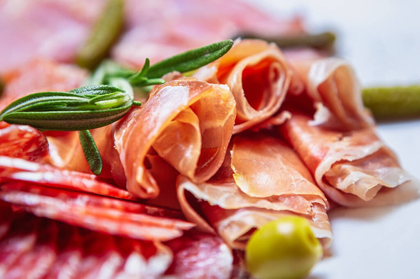 Delicious meat snacks for dinner.Sliced Spanish jamon,pepperoni sausages,beef ham served on plate in restaurant for snack.Gourmet Mediterranean food for wine appetizer - Photo, image