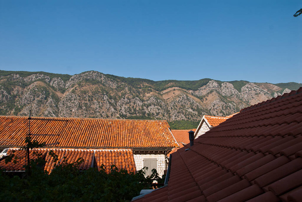 As vistas da montanha através do telhado de azulejos de uma cidade mediterrânica
 - Foto, Imagem