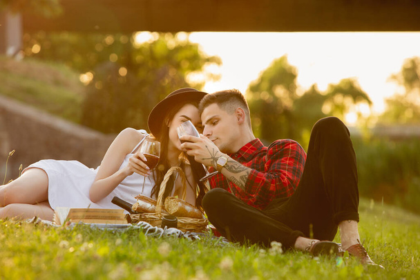 Caucasian young and happy couple enjoying a picnic in the park on summer day - Фото, изображение