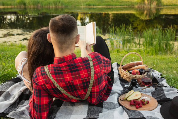 Caucasian young and happy couple enjoying a picnic in the park on summer day - Photo, image