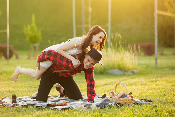 Caucasian young and happy couple enjoying a picnic in the park on summer day - Fotografie, Obrázek