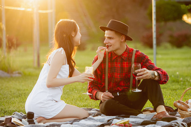 Caucasian young and happy couple enjoying a picnic in the park on summer day - Foto, afbeelding
