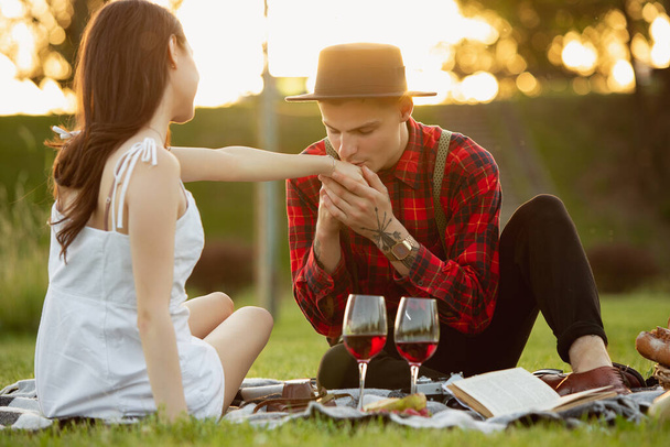 Caucasian young and happy couple enjoying a picnic in the park on summer day - Photo, Image
