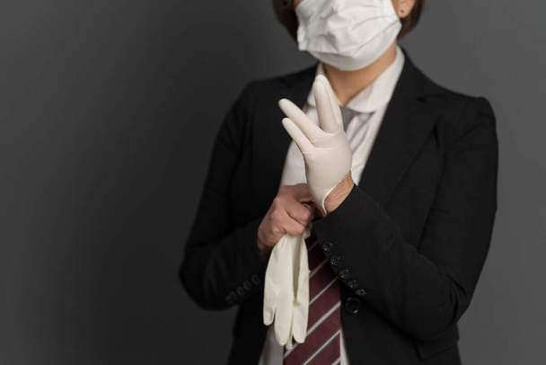 Business Woman in protective mask put on disposable gloves. Close up shot. Focus on female hand in foreground. Pandemic concept - Foto, imagen
