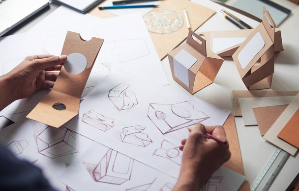 Designer sketching drawing design Brown craft cardboard paper product eco packaging mockup box development template package branding Label . designer studio concept . - Foto, imagen
