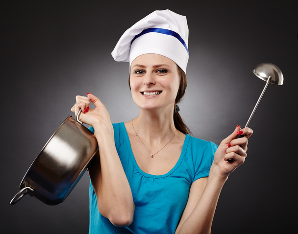 Cheerful woman cook holding a pot and a soup ladle - Fotó, kép