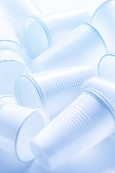 Tazas de plástico blanco desechables como fondo. Concepto ambiental. Residuos no compostables. En tono azul
. - Foto, Imagen