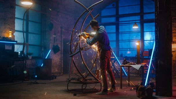 Shot of a Talented Innovative Artist Using an Angle Grinder to Make an Abstract, Brutal and Expressive Metal Sculpture in a Workshop. Contemporary Fabricator Creating Modern Steel Art. - Фото, изображение