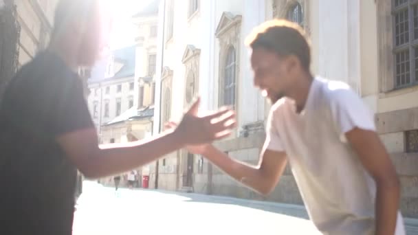 Two African American young men greet each other on a city street. Close portrait, fraternity concept, sun flare - Séquence, vidéo