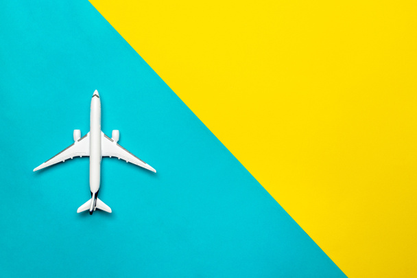 Kids playing toys. White airplane, aircraft in top view on bright blue and yellow backdrop. Flight air plane travel background with copy space for sky fly concept. - Photo, Image