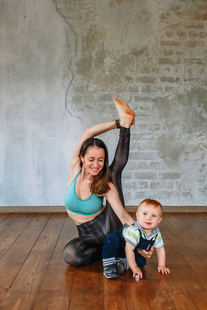 Yoga girl performs an exercise, next to her little son - Foto, Bild