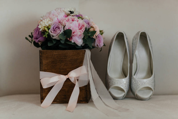 Свадебный букет в деревянной коробке и свадебные каблуки на белом фоне. Подготовка невесты. Цветы
 - Фото, изображение