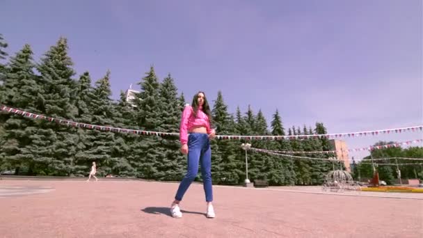 Eşofmanlı, uzun saçlı, enerjik genç bir kadın sokak dansı yapıyor. Şehir parkında açık bir alanda hip hop yapıyor. Gençlik alt kültürü. Çağdaş koreografi. Gimbal atışı. - Video, Çekim