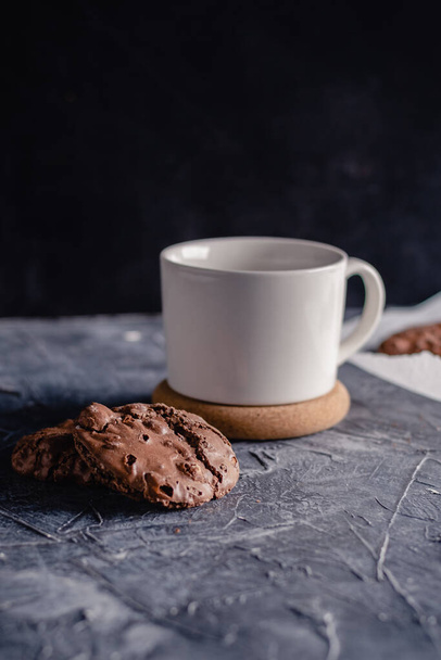 White cup of coffee and chocolate cookie on black stone background. Sweet, copy. Homemade cookies with chocolate. - Foto, afbeelding