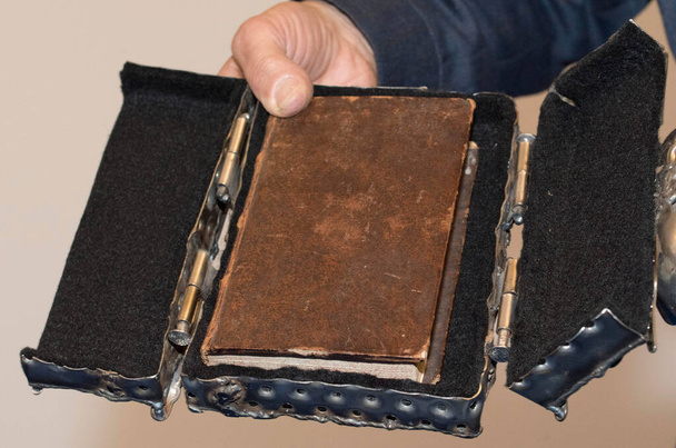 πρόσωπο που κατέχει ένα αρχαίο βιβλίο, το οποίο τίθεται σε μια περίπτωση, στο χέρι του - Φωτογραφία, εικόνα
