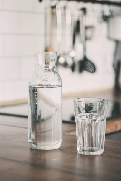 A carafe of water on the kitchen wooden table. Bottle of water. the concept of a healthy lifestyle - Foto, immagini