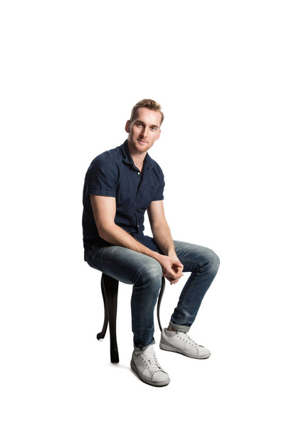 A picture of a European male sittingcasually on a stool loving his weekend wearing casual clothes. - Foto, Imagen