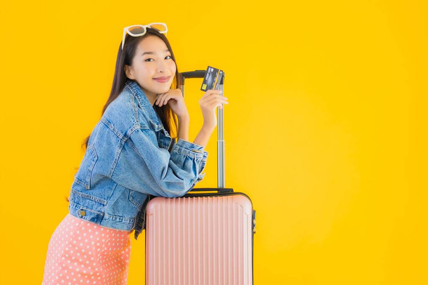 Retrato bela jovem mulher asiática com bagagem saco de viagem com passaporte e bilhete de embarque no fundo isolado amarelo
 - Foto, Imagem